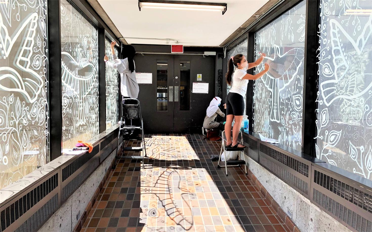 Students paint a bird mural on the window