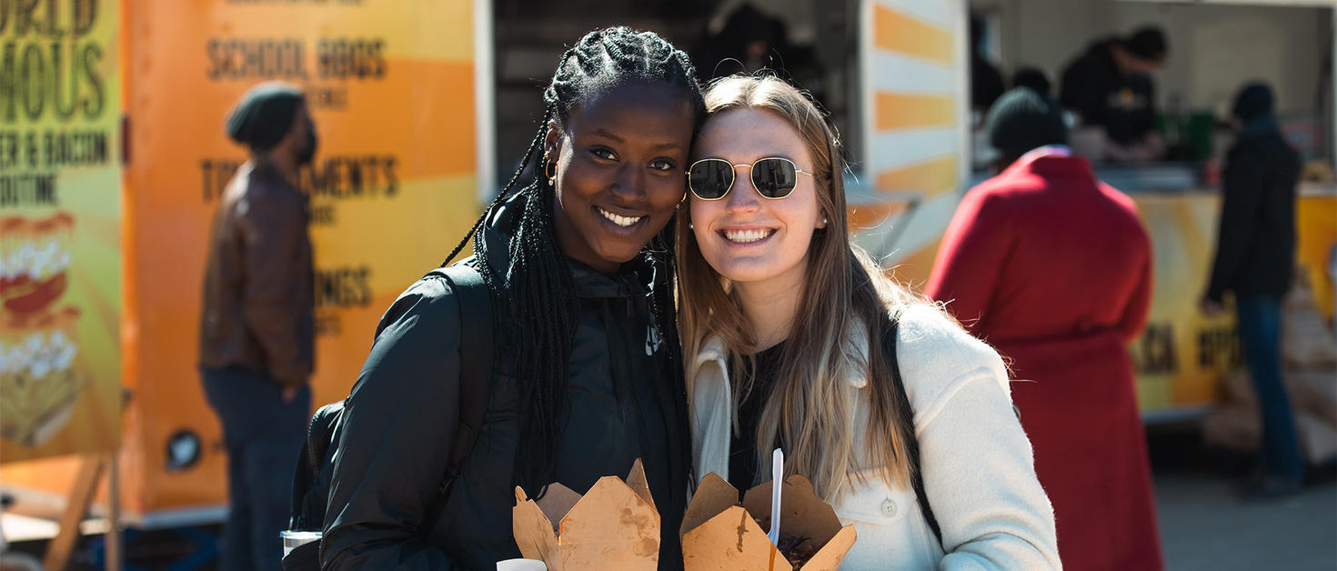Two girls holding poutine boxes