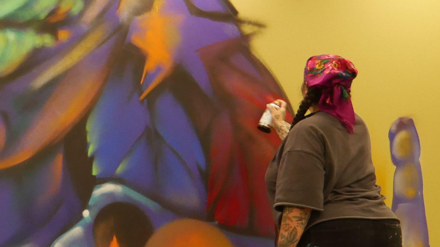 Artist Michelle Mique painting in the Morisset Library 