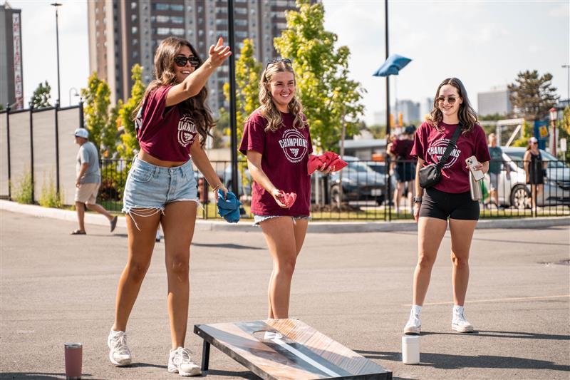 Three women playing cornhole on campus