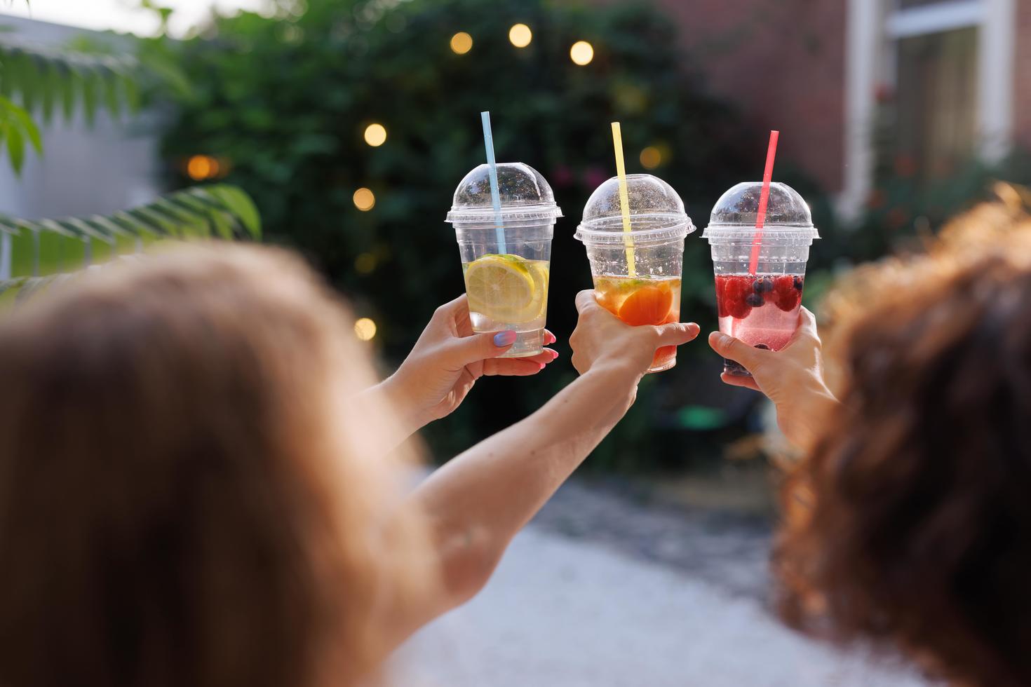 Three people holding three tropical drinks at arm's length