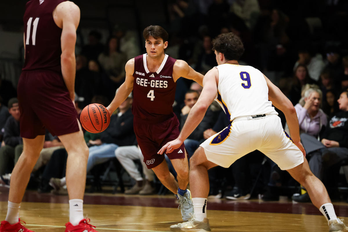 Gee-Gee's men's basketball player dribbles by a player from Laurier