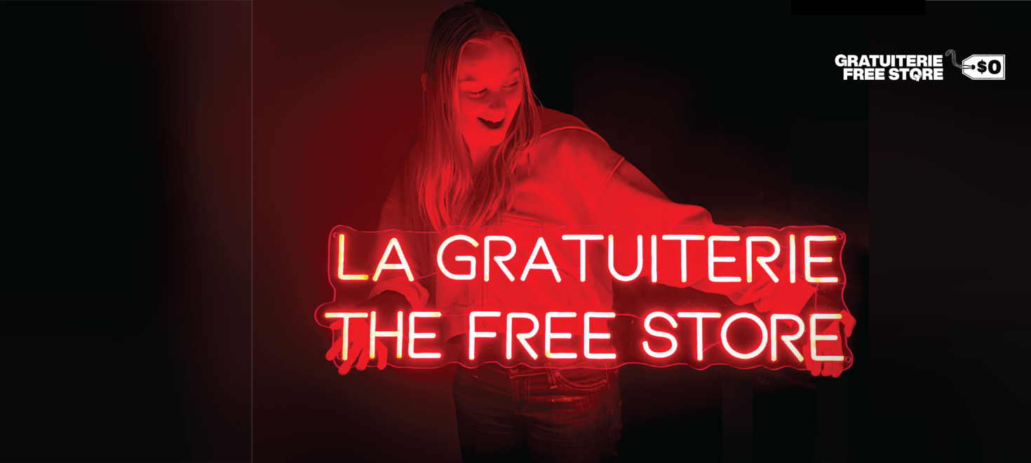A student holding up a neon sign for the Free Store