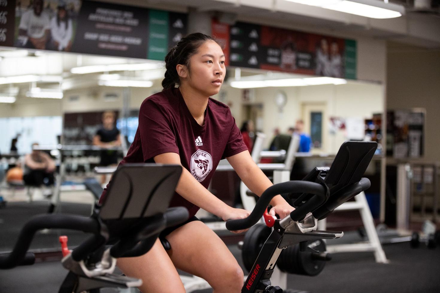 A female student exercises on a stationary bike.