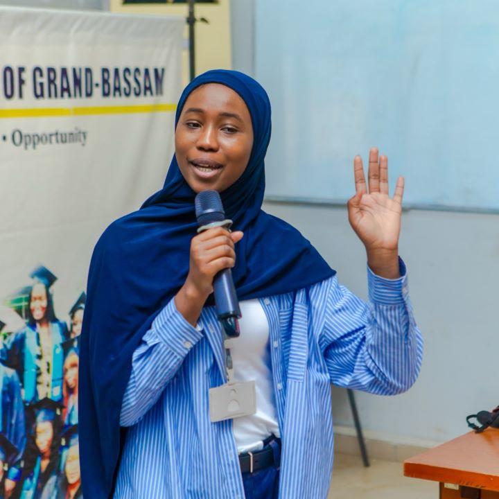 Kady Diarrassouba speaks through a microphone as she leads Mots sur maux writing workshops.