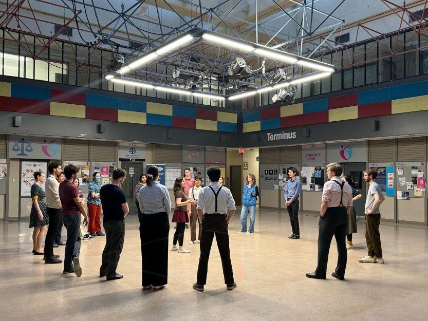 Student dancers of the uoSwing Club stand in a circle inside a rehearsal space.