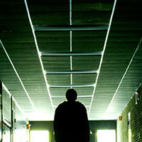 Outline of a person silhouette walking down a dark school hallway 