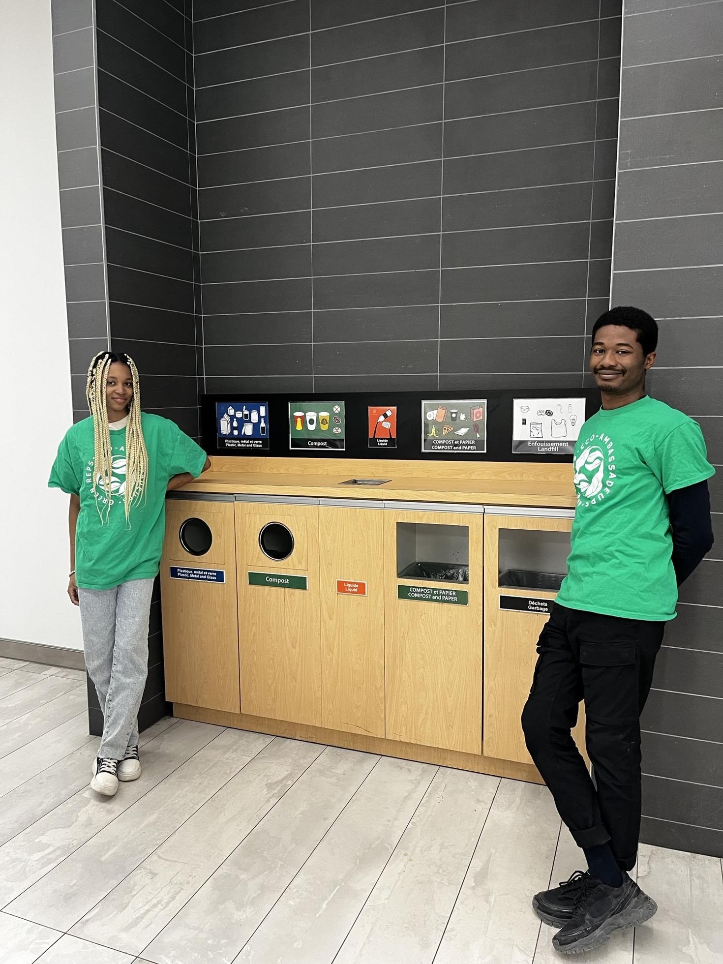Two Green Reps students smiling next to a recycling station