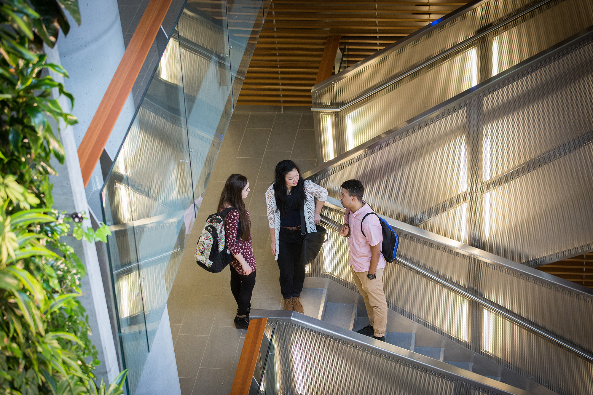 Three students standing on a staircase.