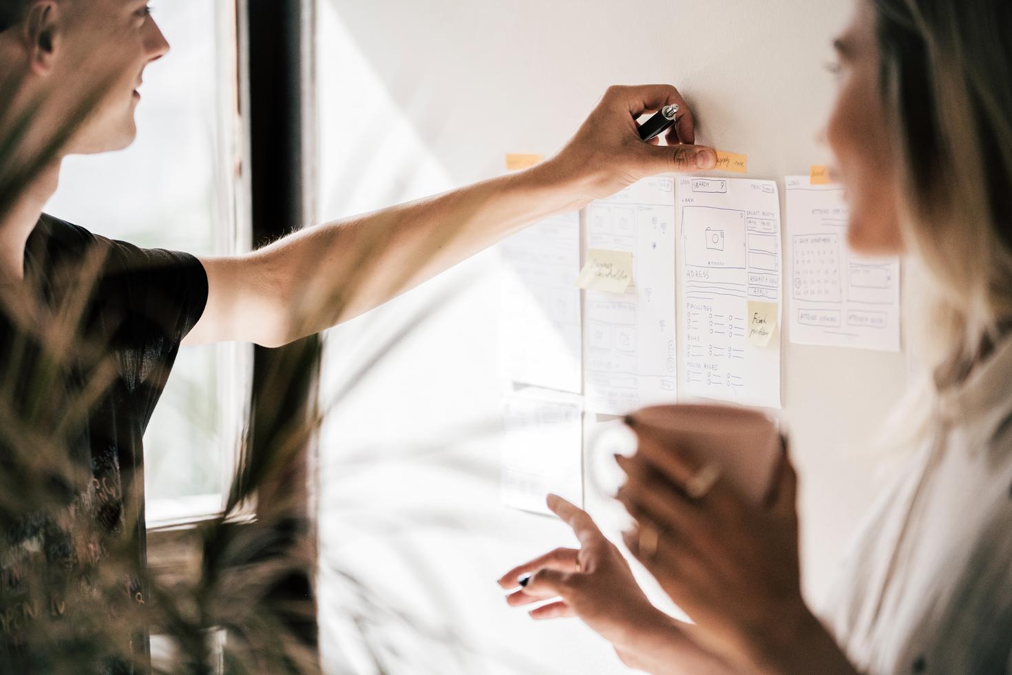 Two people attaching idea notes to a wall