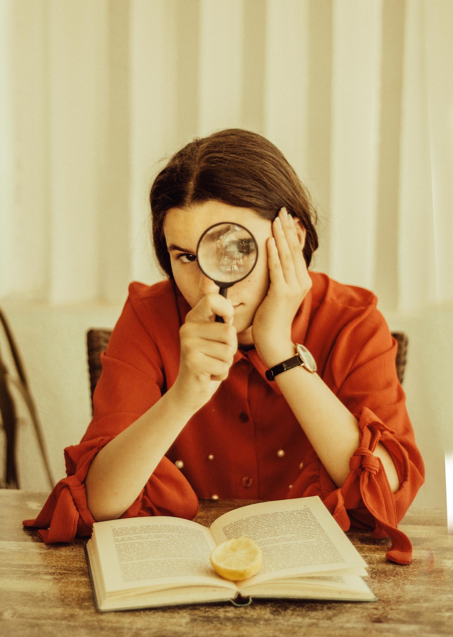 Young woman looking through a magnifying glass