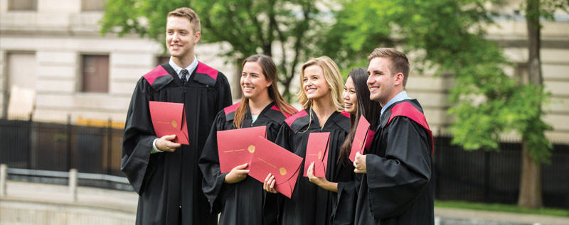 Group of graduating students posing for a photo with diplomas in hand