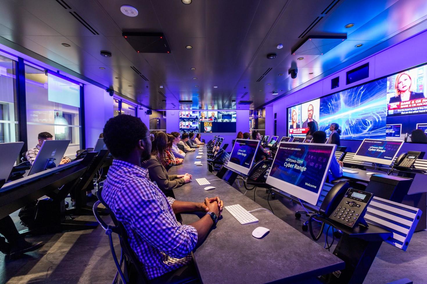 A control room filled with many large computer screens.
