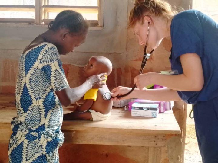 A medical student examines a baby with a stethoscope.