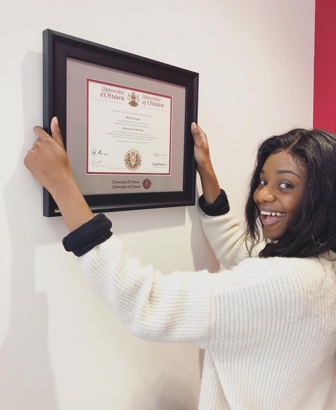 Un étudiant accroche son diplôme encadré au mur.