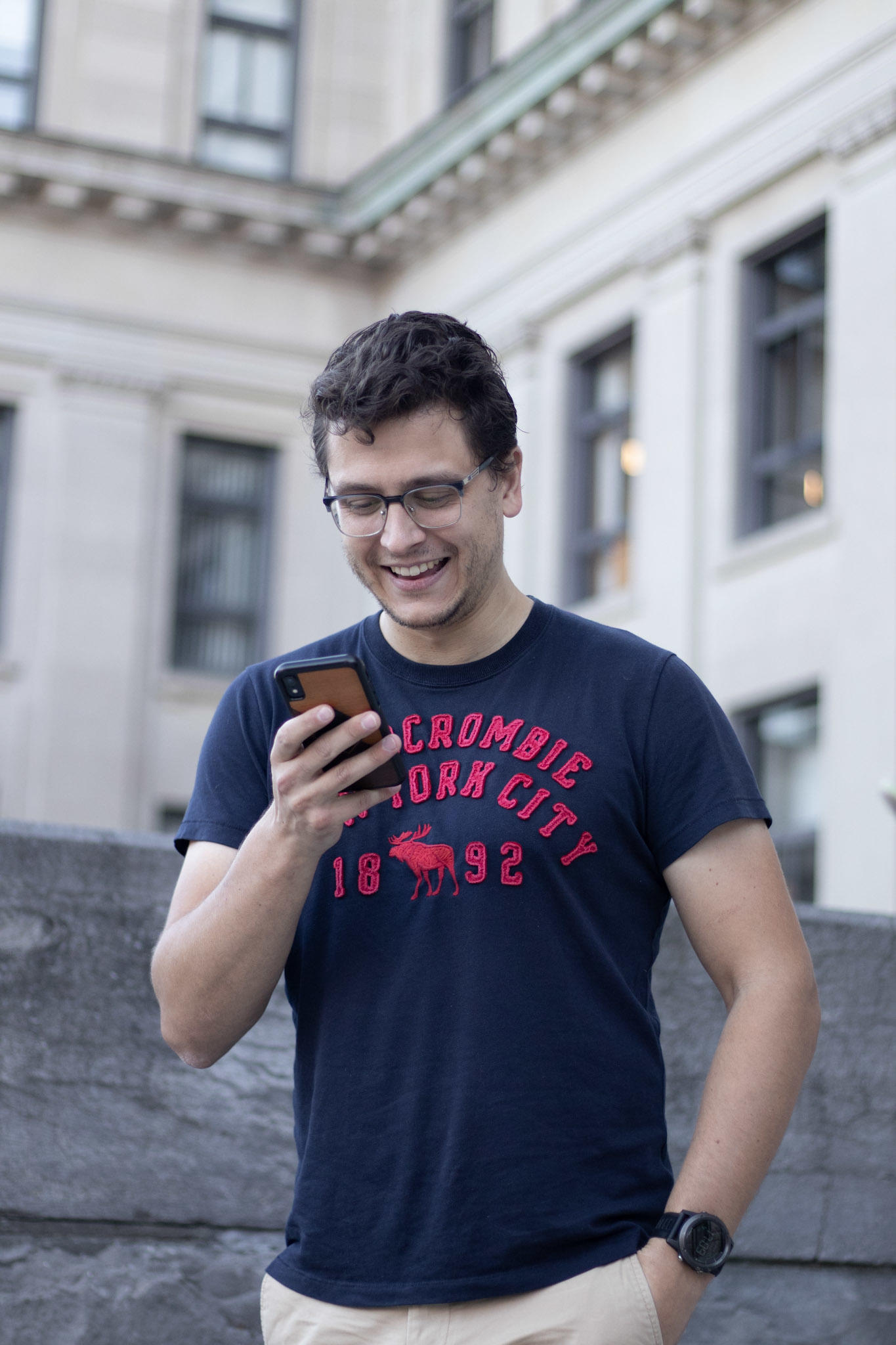 Un diplômé de l'Université d'Ottawa riant regardant son téléphone.