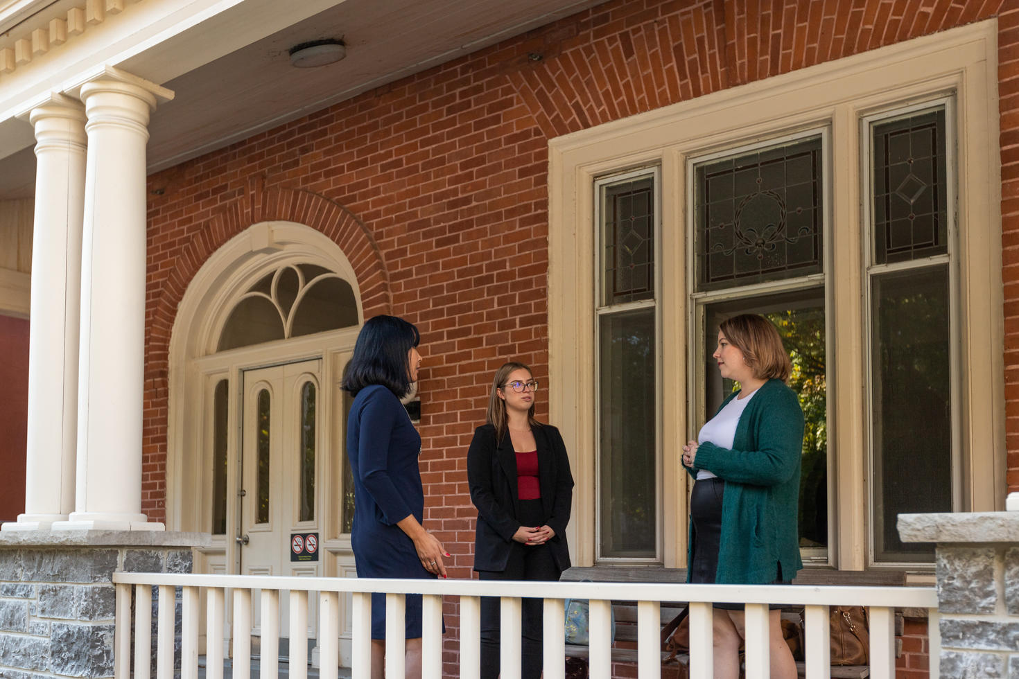 Trois personnes discutent à l'extérieur de l'Alumni Hall.