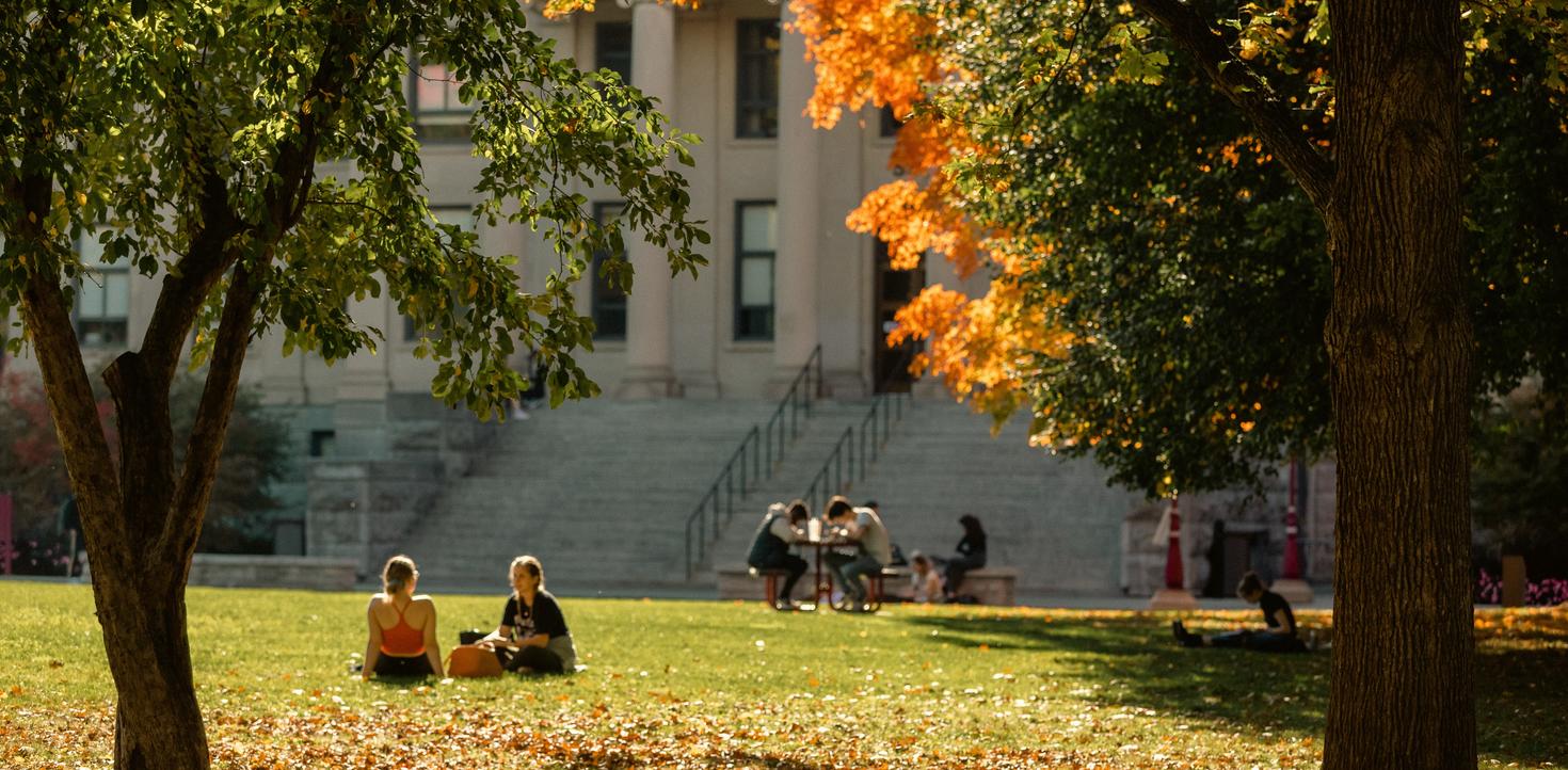 Des étudiants assis sur la pelouse de Tabaret en automne.