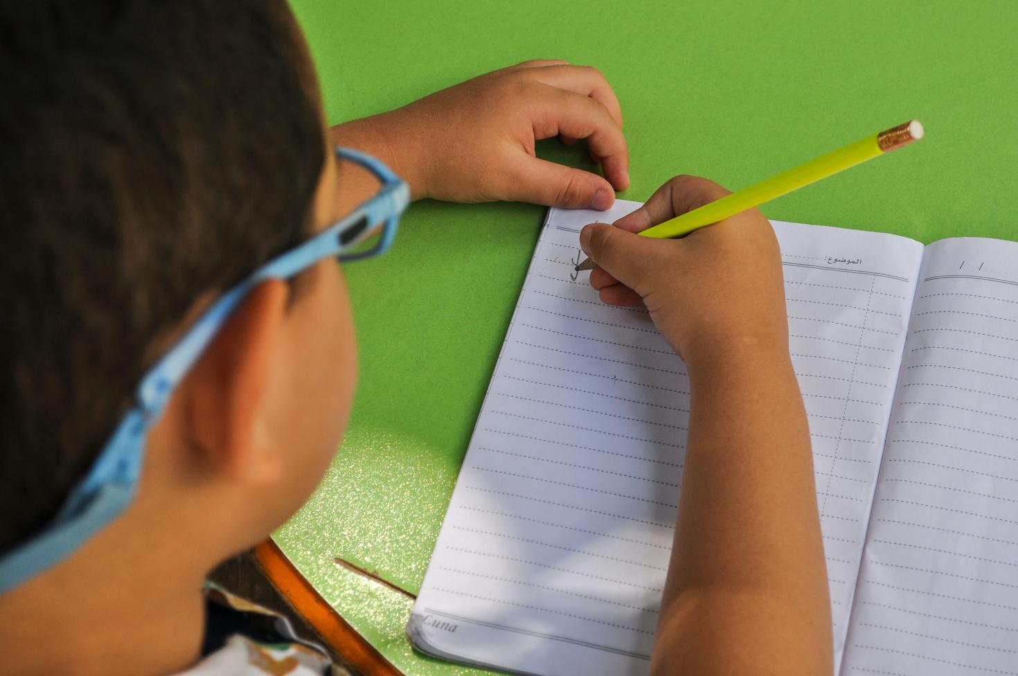 Un enfant écrit sur un cahier d'exercices