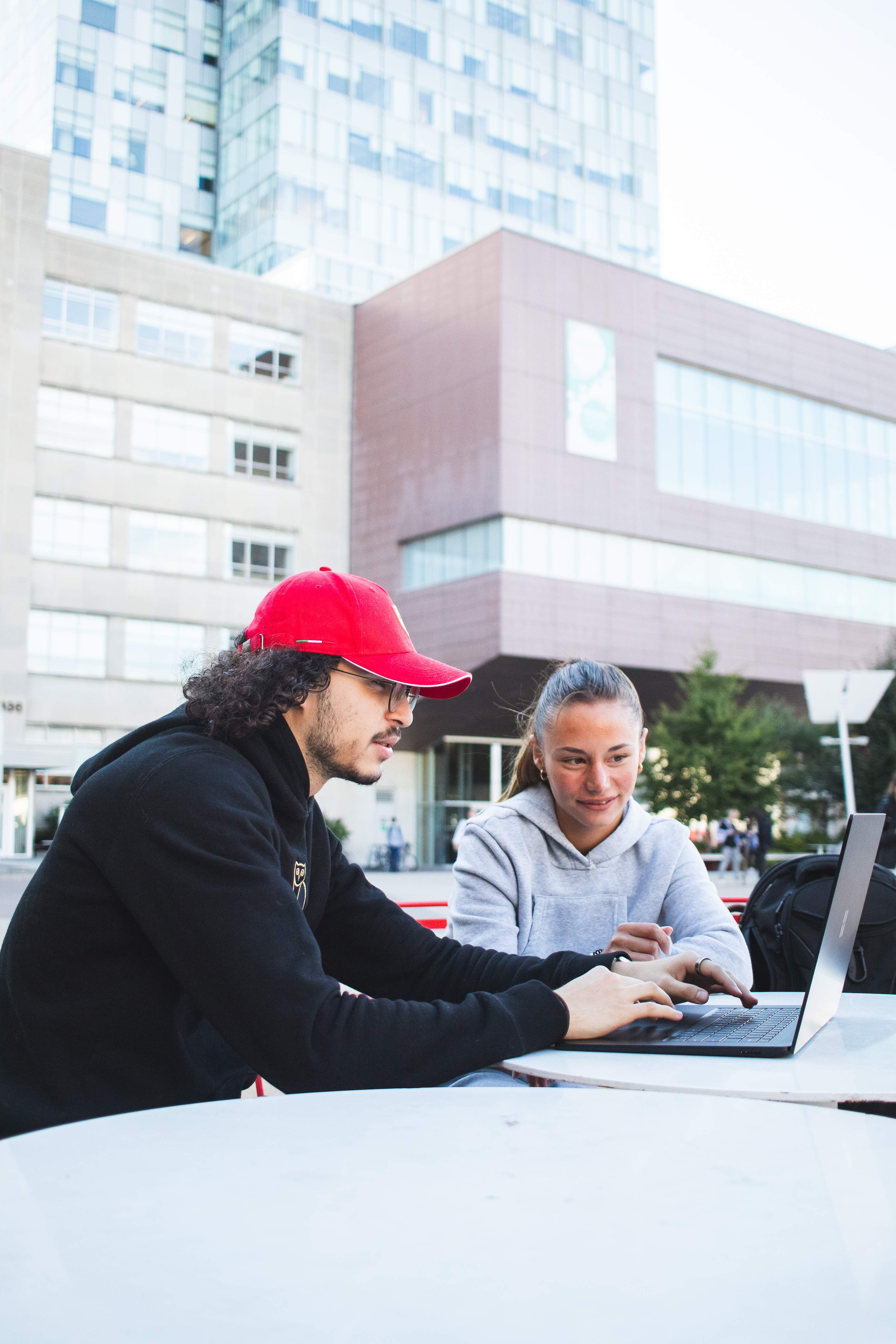 Sétudiants assis à l'extérieur, regardant sur un ordinateur portable