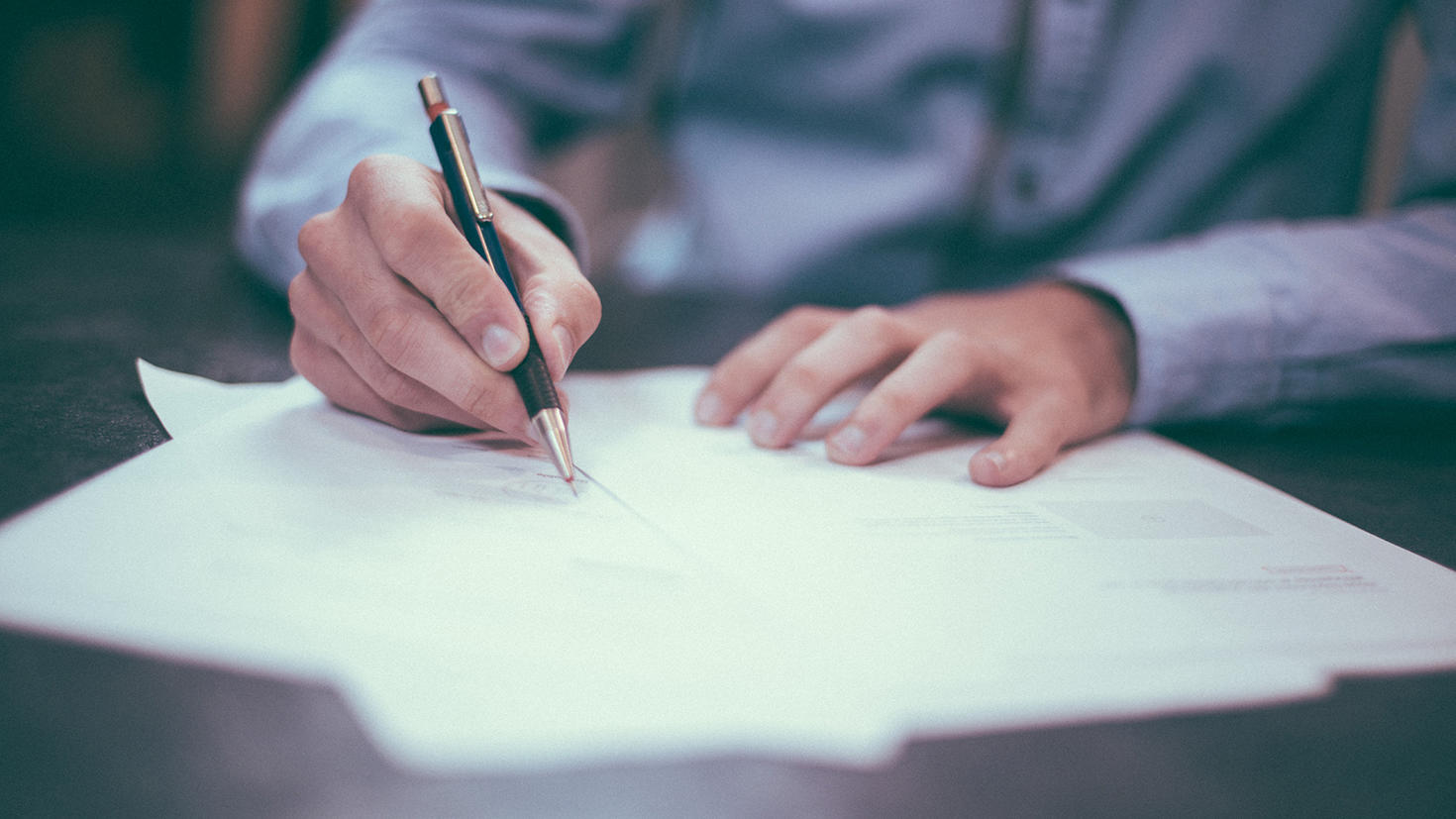 vue des mains d'une personne qui signe des documents