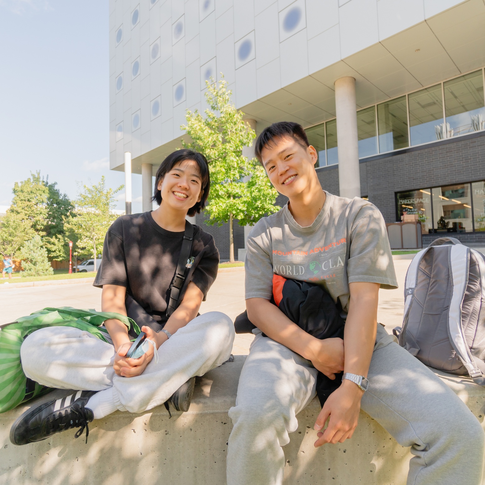 deux étudiants souriants assis devant l'édifice STEM