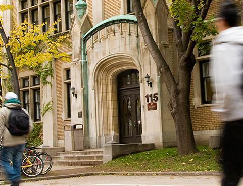 graduate students walking by main doors of historic arts building in fall