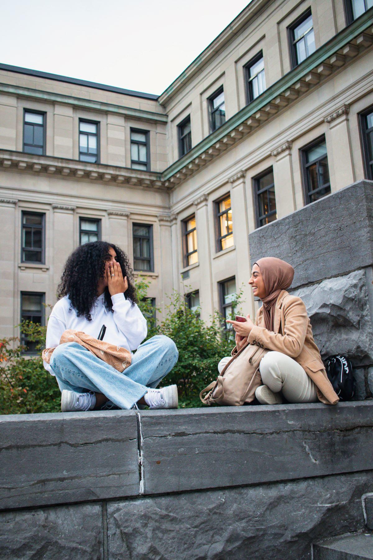 des étudiants assis devant le Tabaret Hall et discutant.