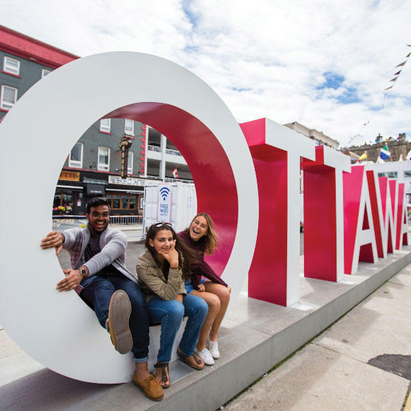 étudiants assit sur les lettres Ottawa