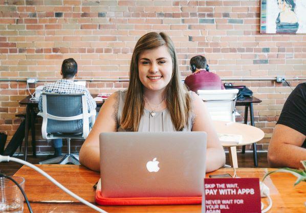 étudiant assis à un bureau, souriant et faisant face à la caméra