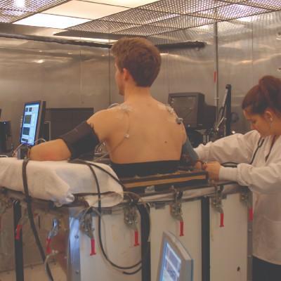 Un patient subit un examen physique dans un laboratoire. Des capteurs sont collés à son dos.