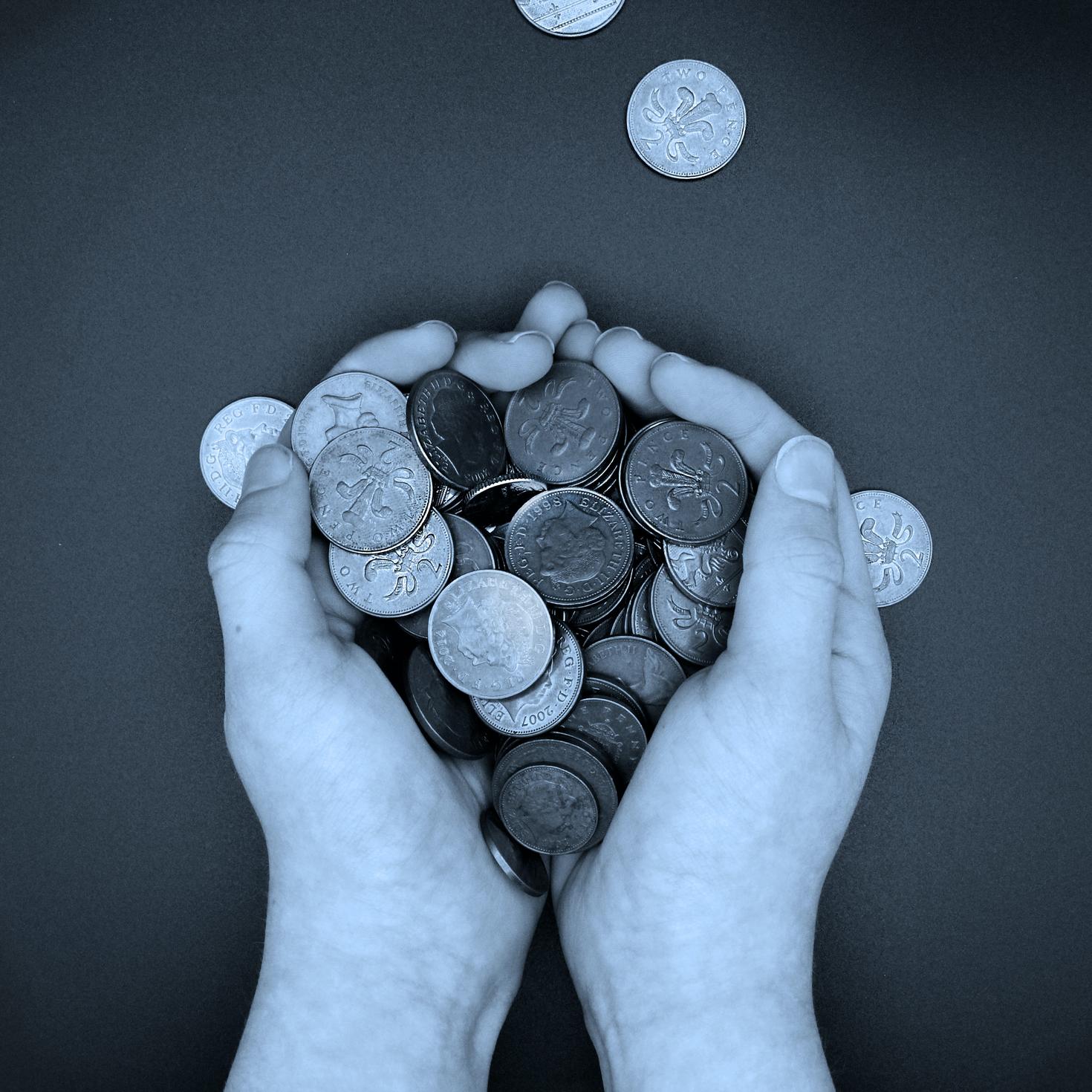 Personne tenant une pile de pièces de monnaie à la main.