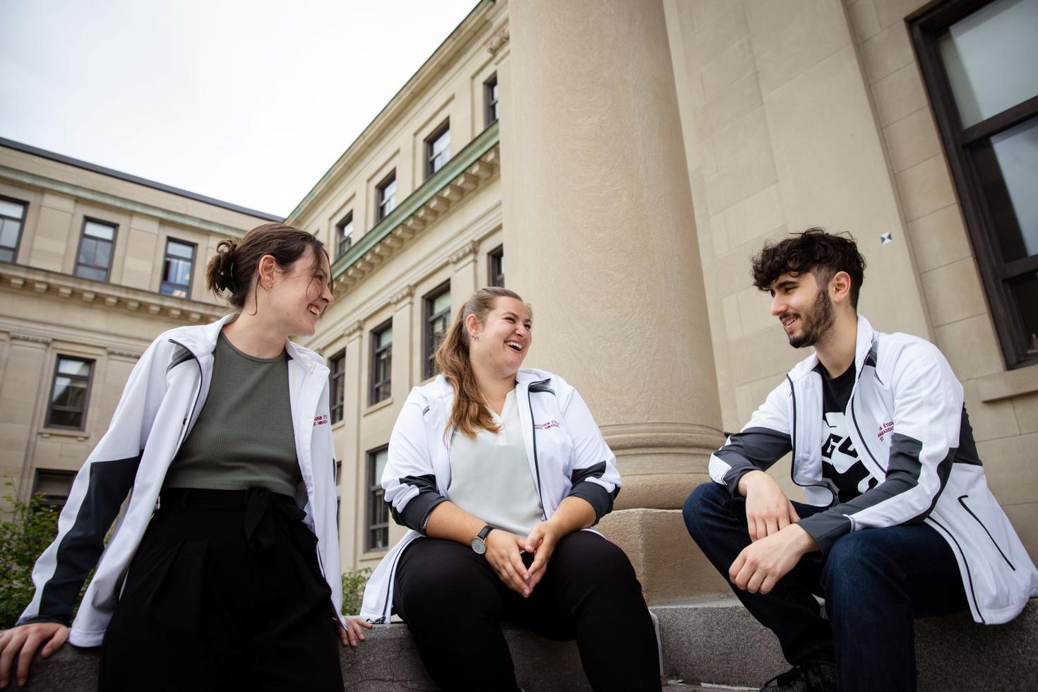Étudiantes et étudiants ambassadeurs assis devant le pavillon Tabaret.