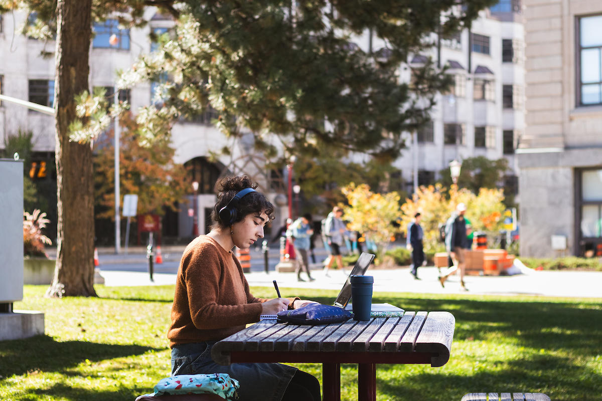Un étudiant étudie sur une table de pique-nique à l'extérieur.