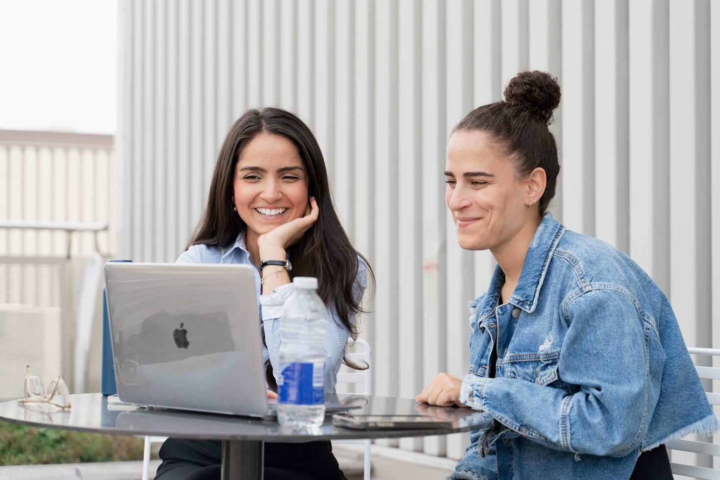 2 students sitting at a table with a laptop