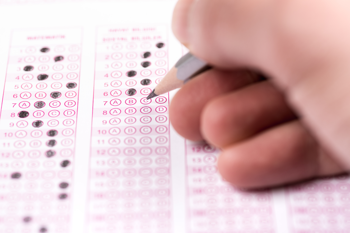 Main tenant un crayon et remplissant des cercles sur une feuille de scantron.