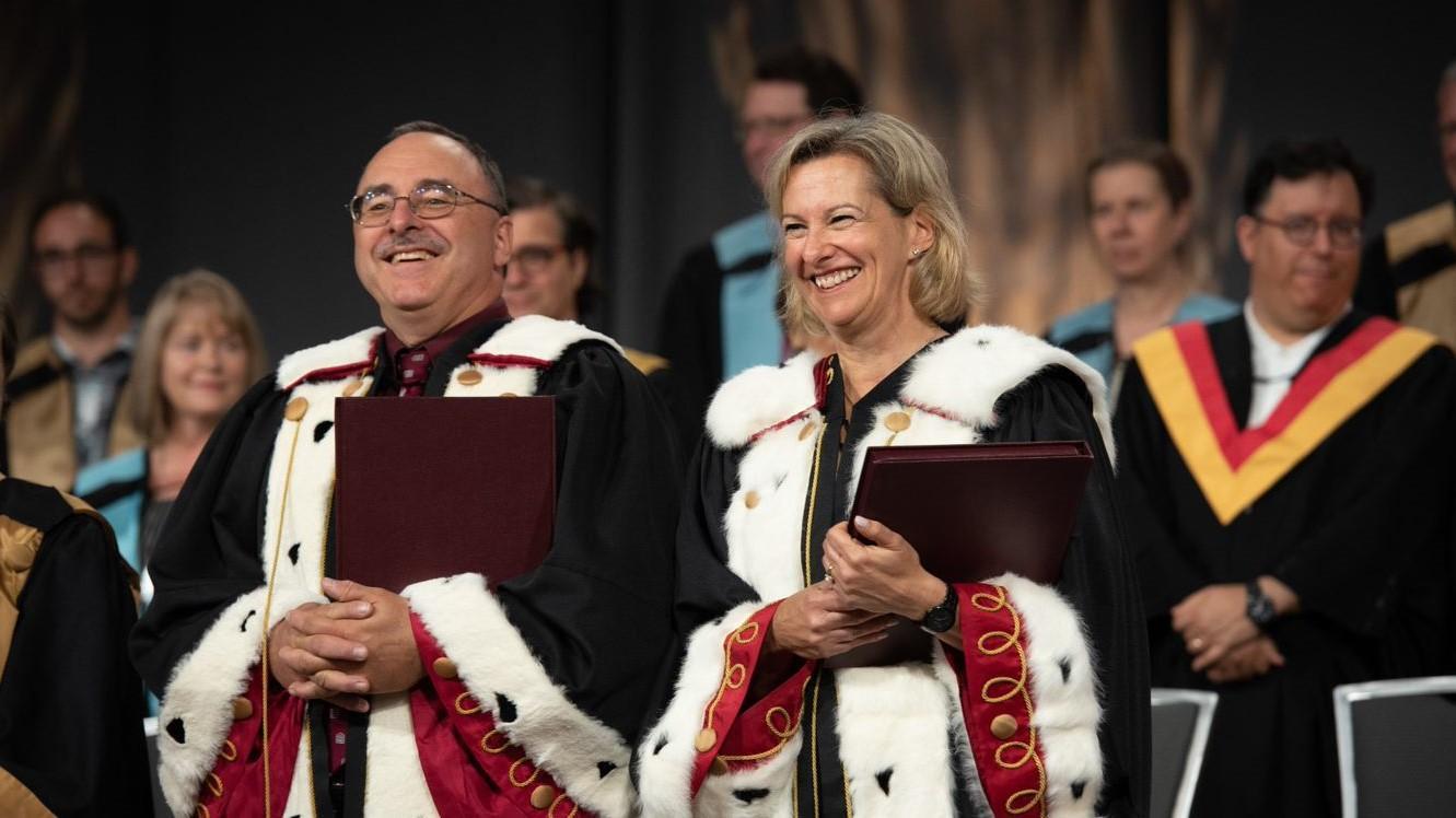 deux dignitaires universitaires debout sur la scène de la collation des grades