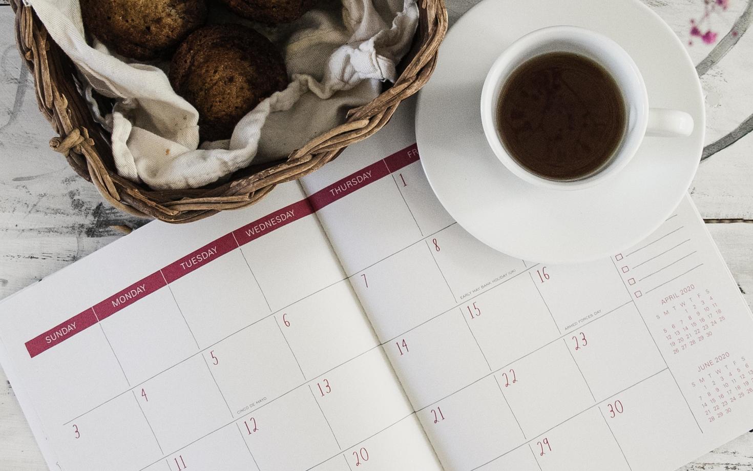 Calendrier en papier avec une tasse à café à côté.