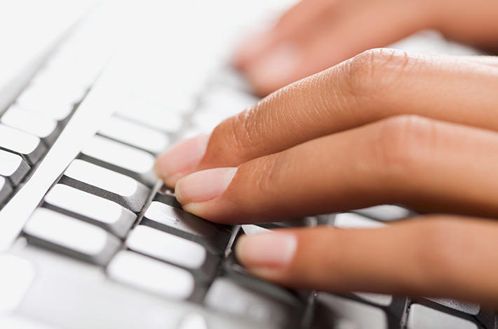 Doigts tapant sur le clavier d'un ordinateur portable.