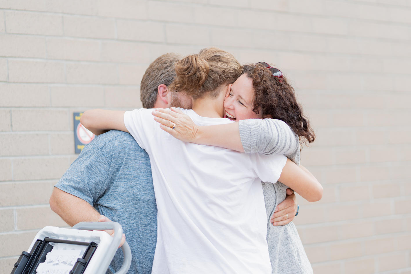Parents hugging their daughter.