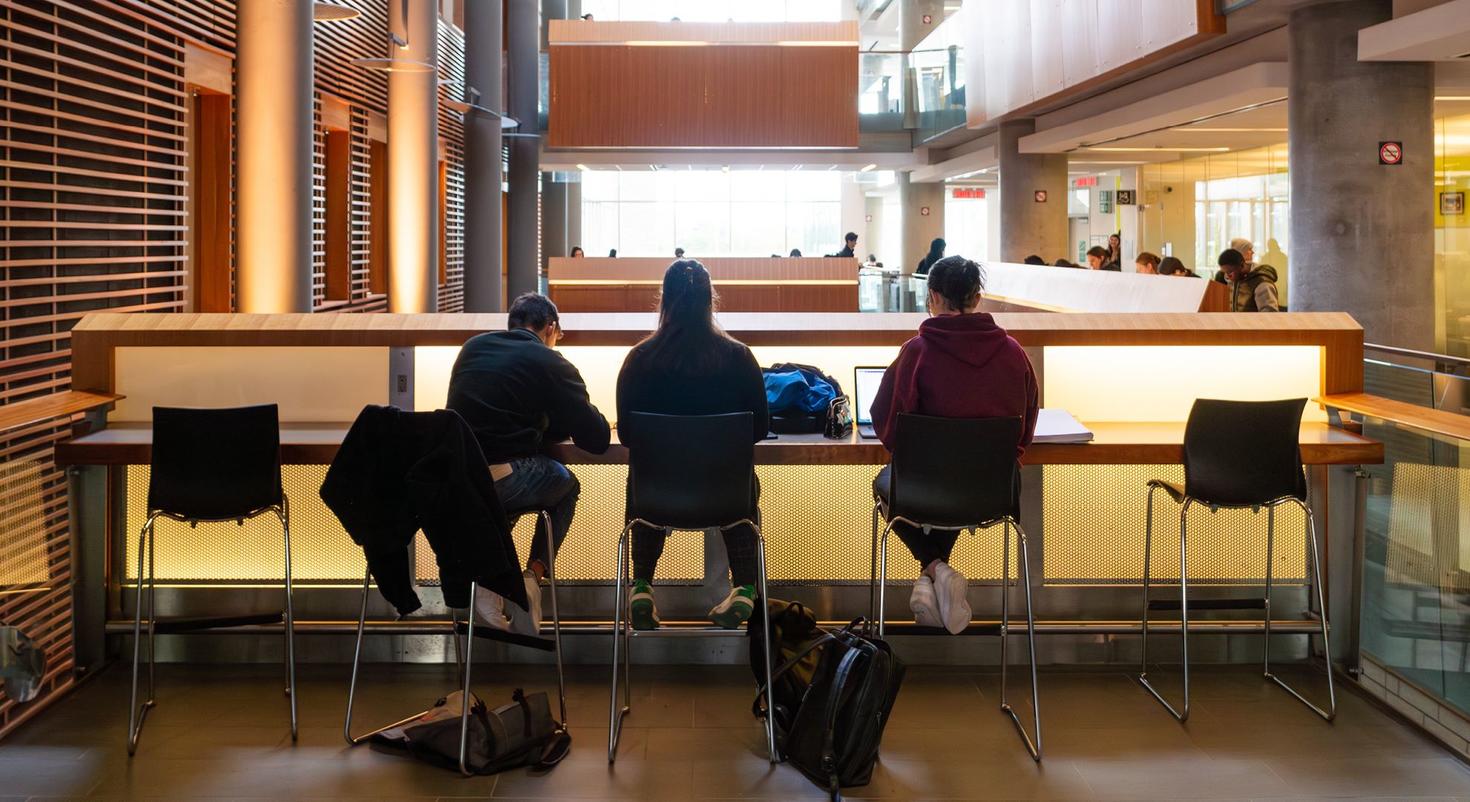 Trois étudiants en silhouette étudient à l'intérieur du bâtiment FSS.