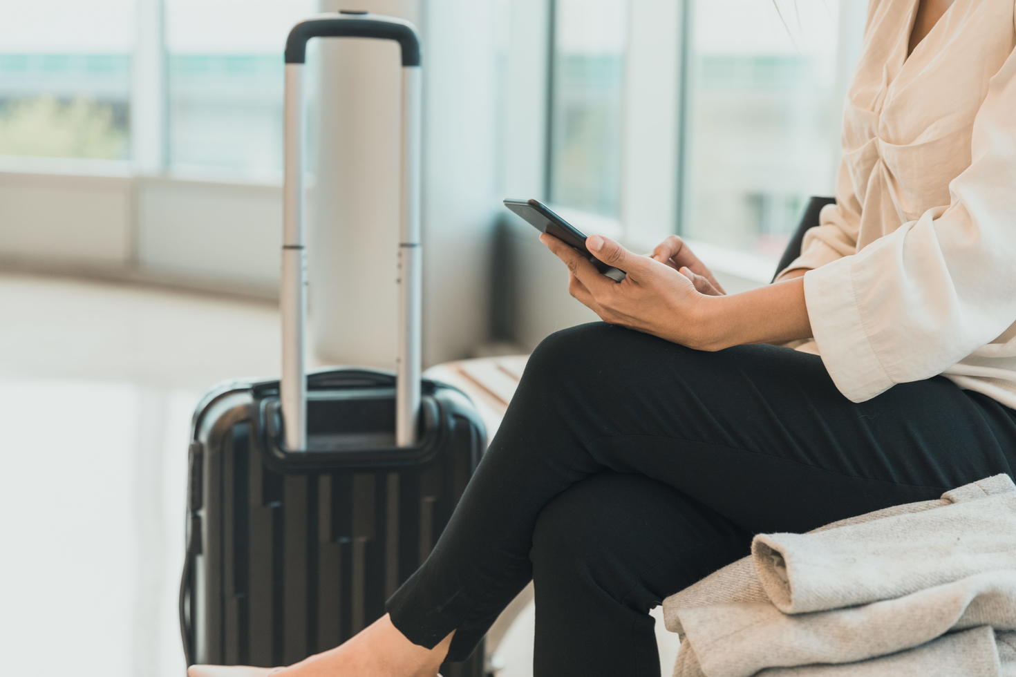 Girl with suitcase at the airport, looking at phone