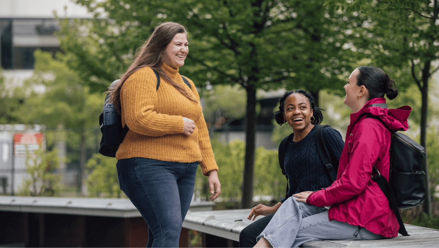 Trois étudiantes et étudiants en train de parler et de sourire.