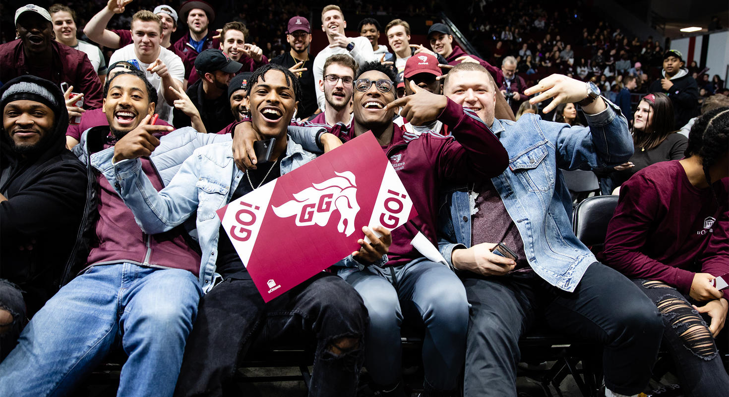 Des étudiants qui sourient en regardant une partie des Gee-Gees.