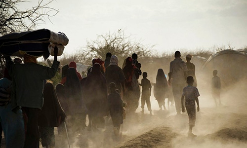 Grand groupe de personnes marchant dans un environnement aride.