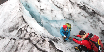 Deux personnes escaladent une paroie glacée.