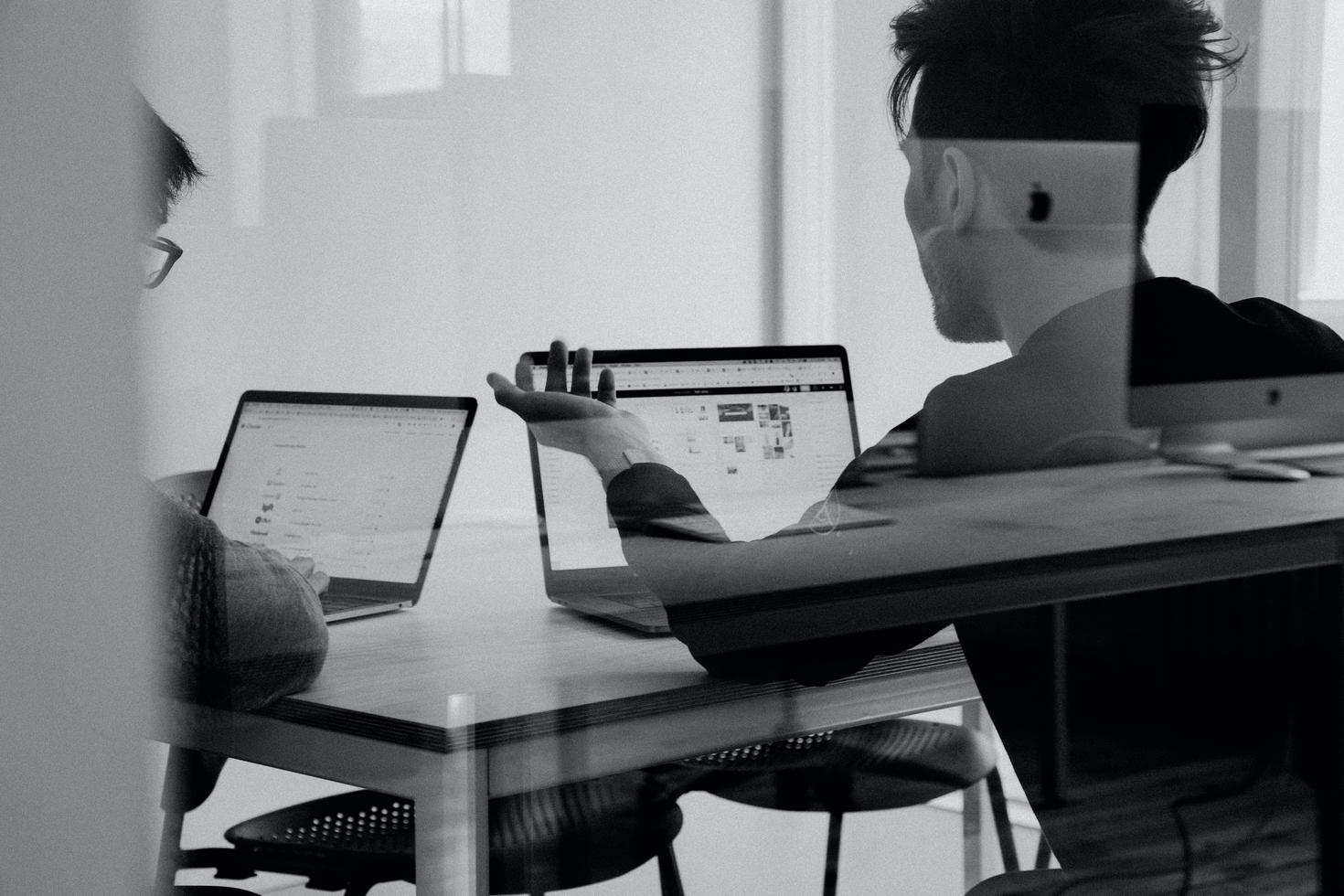 Vue d'étudiants à travers une fenêtre, travaillant sur un ordinateur portable.