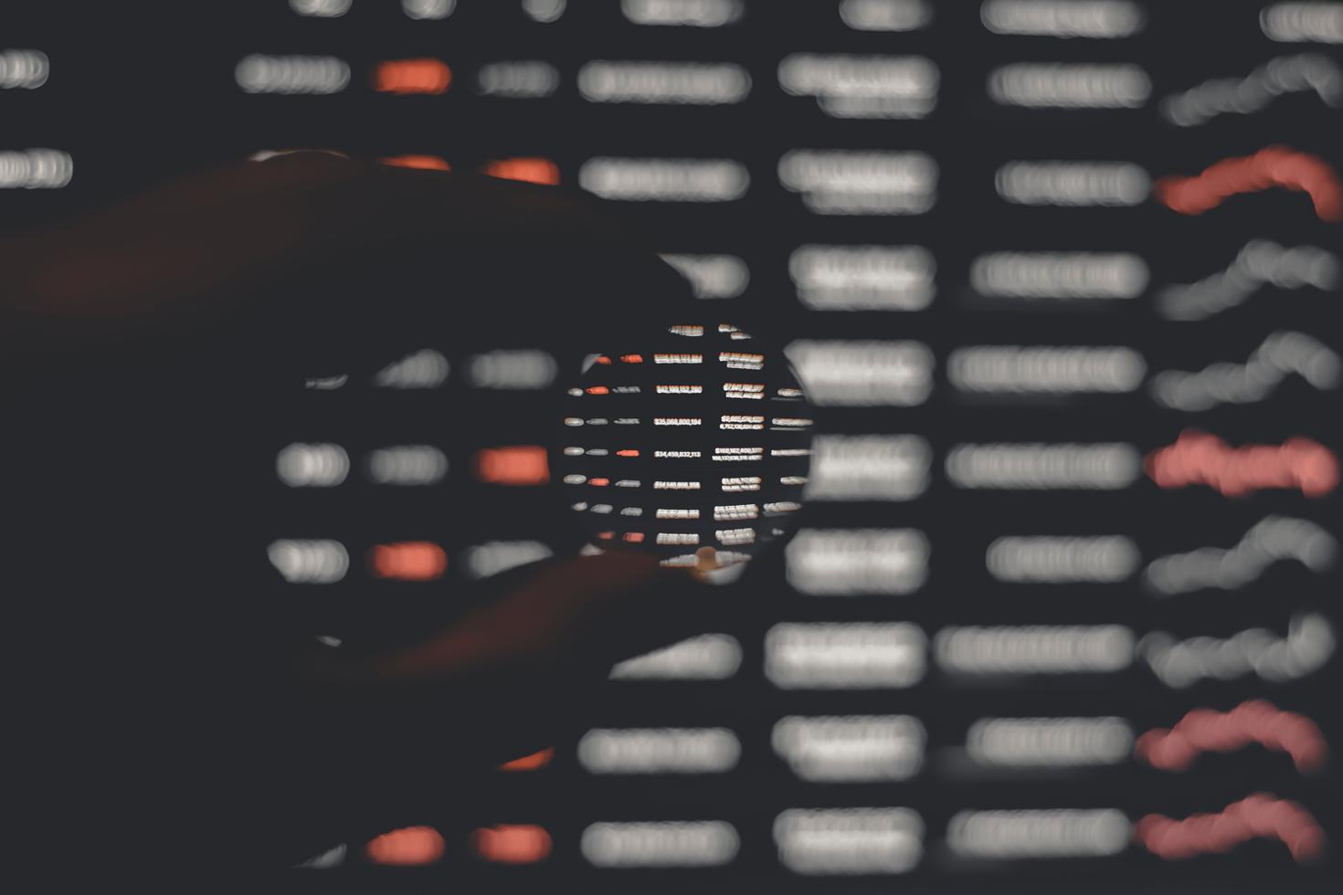 Close up on fingers holding a round piece of glass and seeing code through it