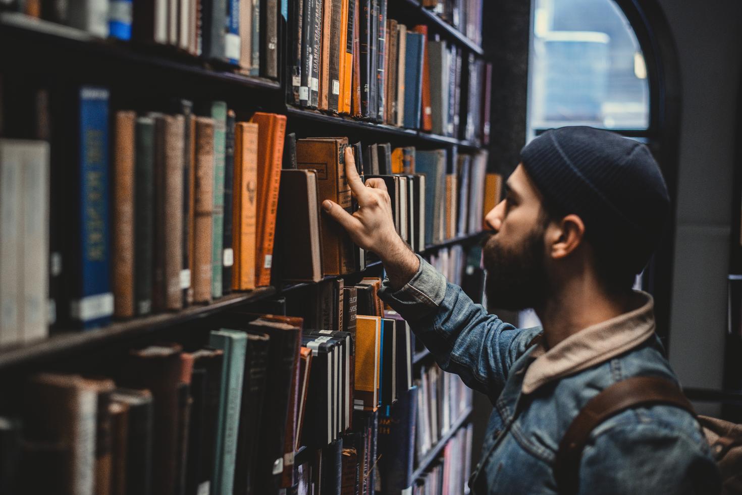 Homme prenant un livre sur l'étagère d'une bibliothèque