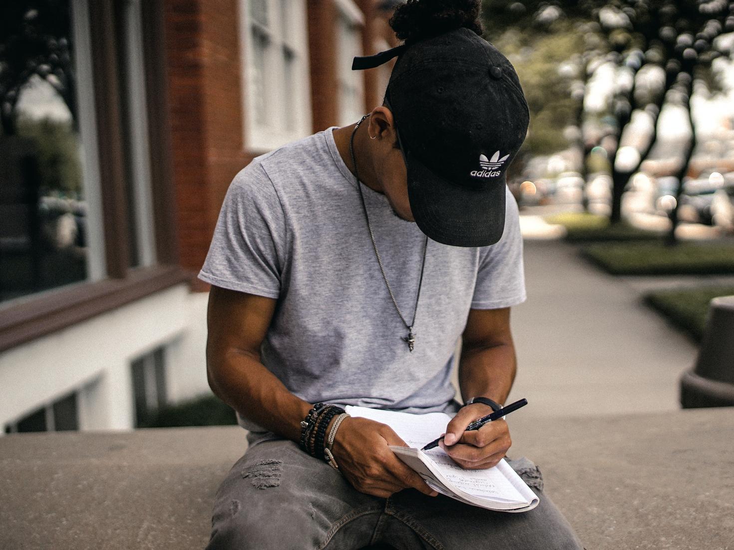 gars avec une casquette écrivant